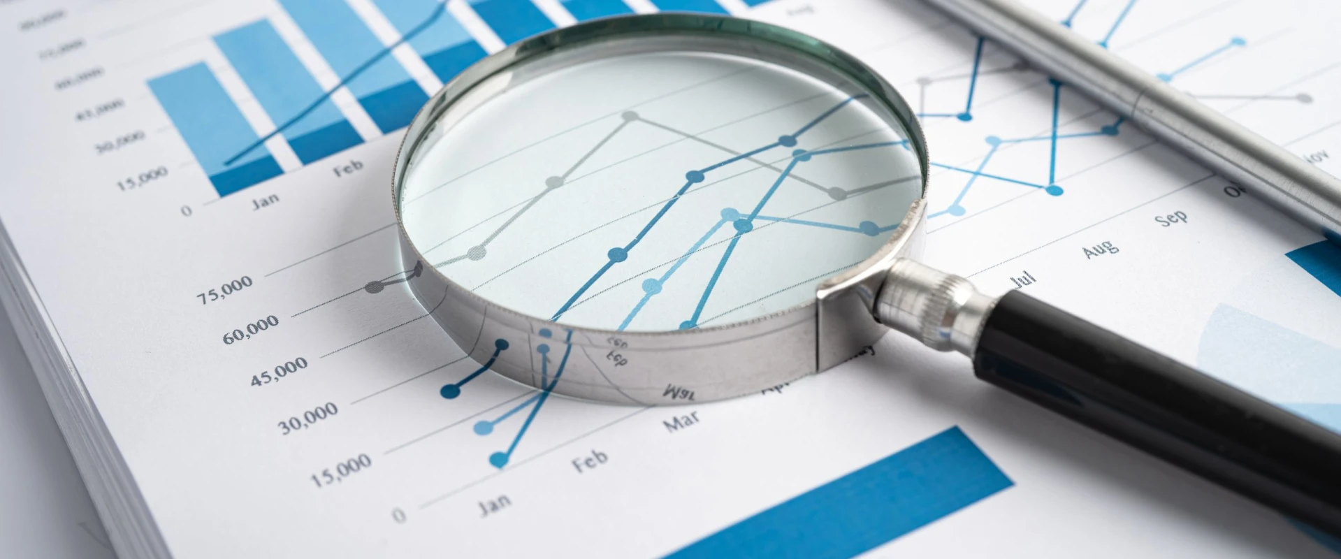 Magnifying glass on a line chart on paper.