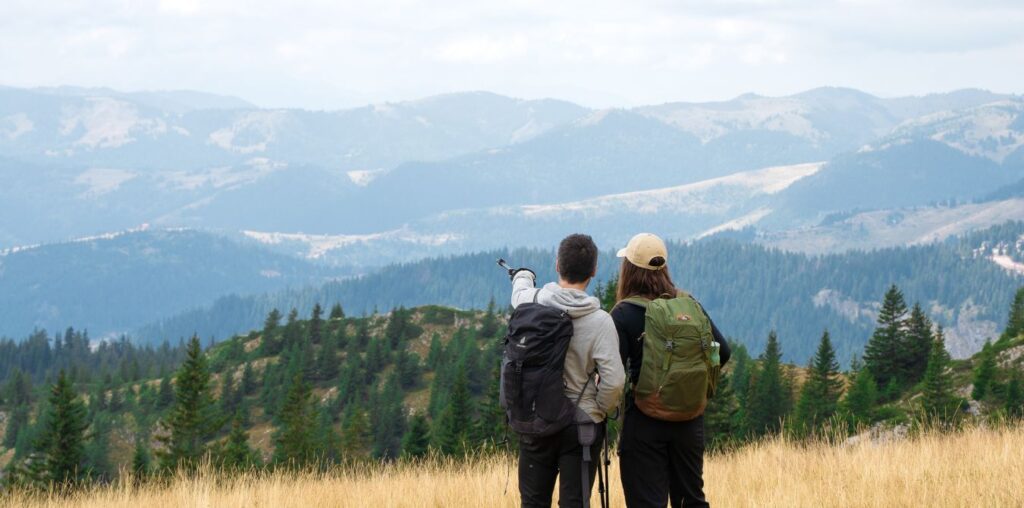 A couple is standing in a picturesque wilderness with mountain scenery in the distance