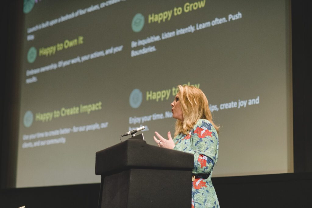 Jaye Cowle, Founder of Launch, on a podium at a Launch event